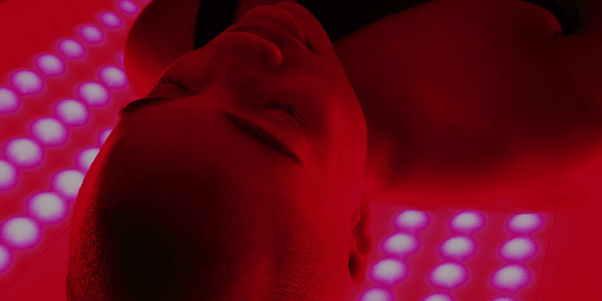 a close up shot of a woman laying on her back in an infrared light chamber