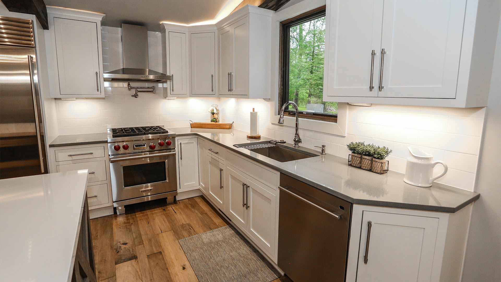 detail shot of the kitchen. There are white shelves with silver hardware. There is ample counter space and a large farm sink. There is a dishwasher and stove and oven.