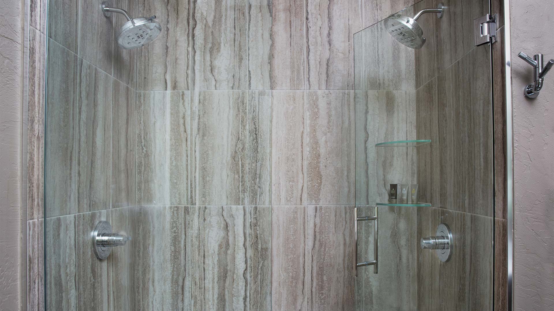 a detail shot of a shower with light gray wood paneling and two shower heads