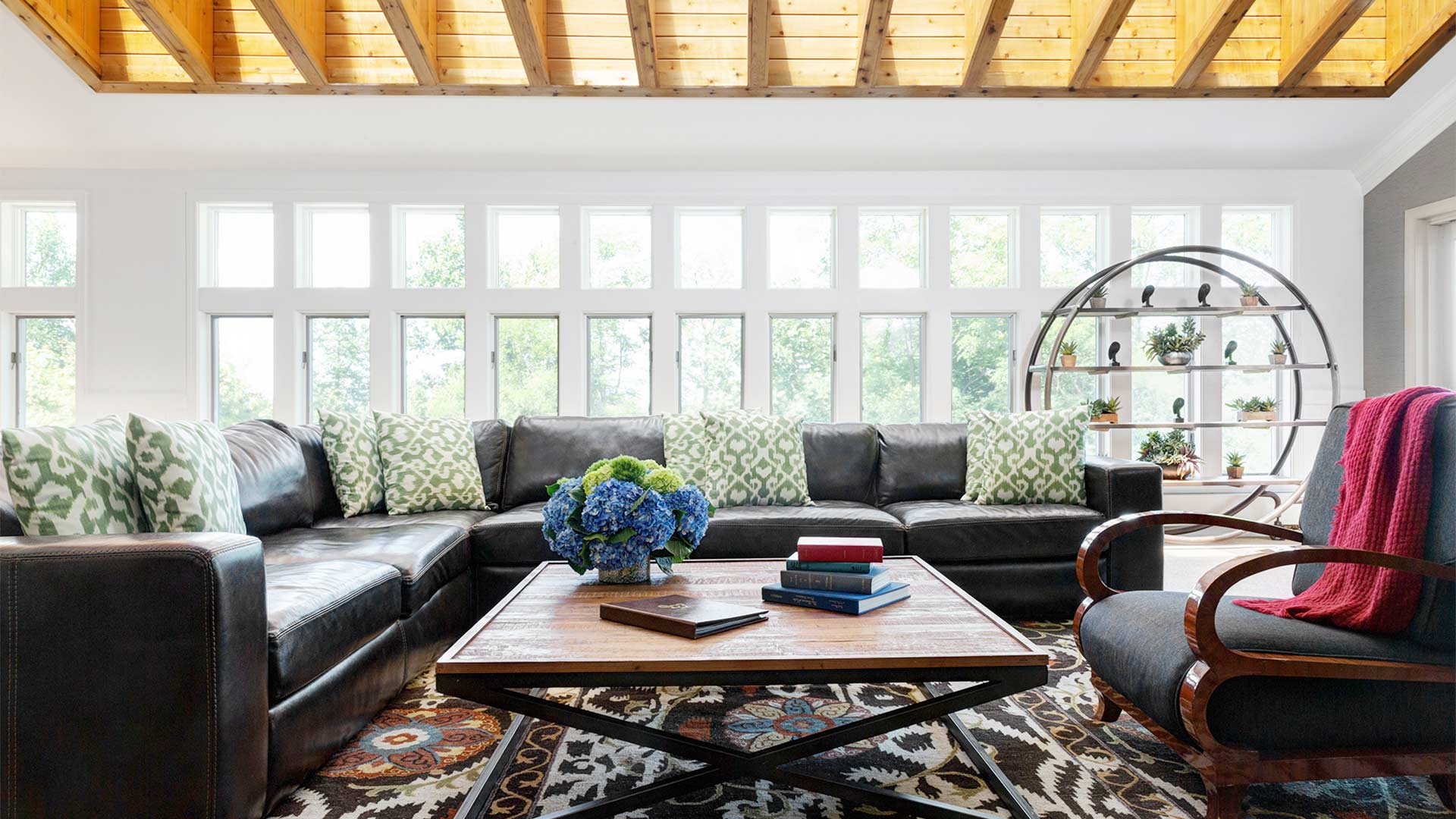 interior shot of the arden living area. There are couches and arm chairs surrounding a wood coffee table. There are windows surrounding the room.