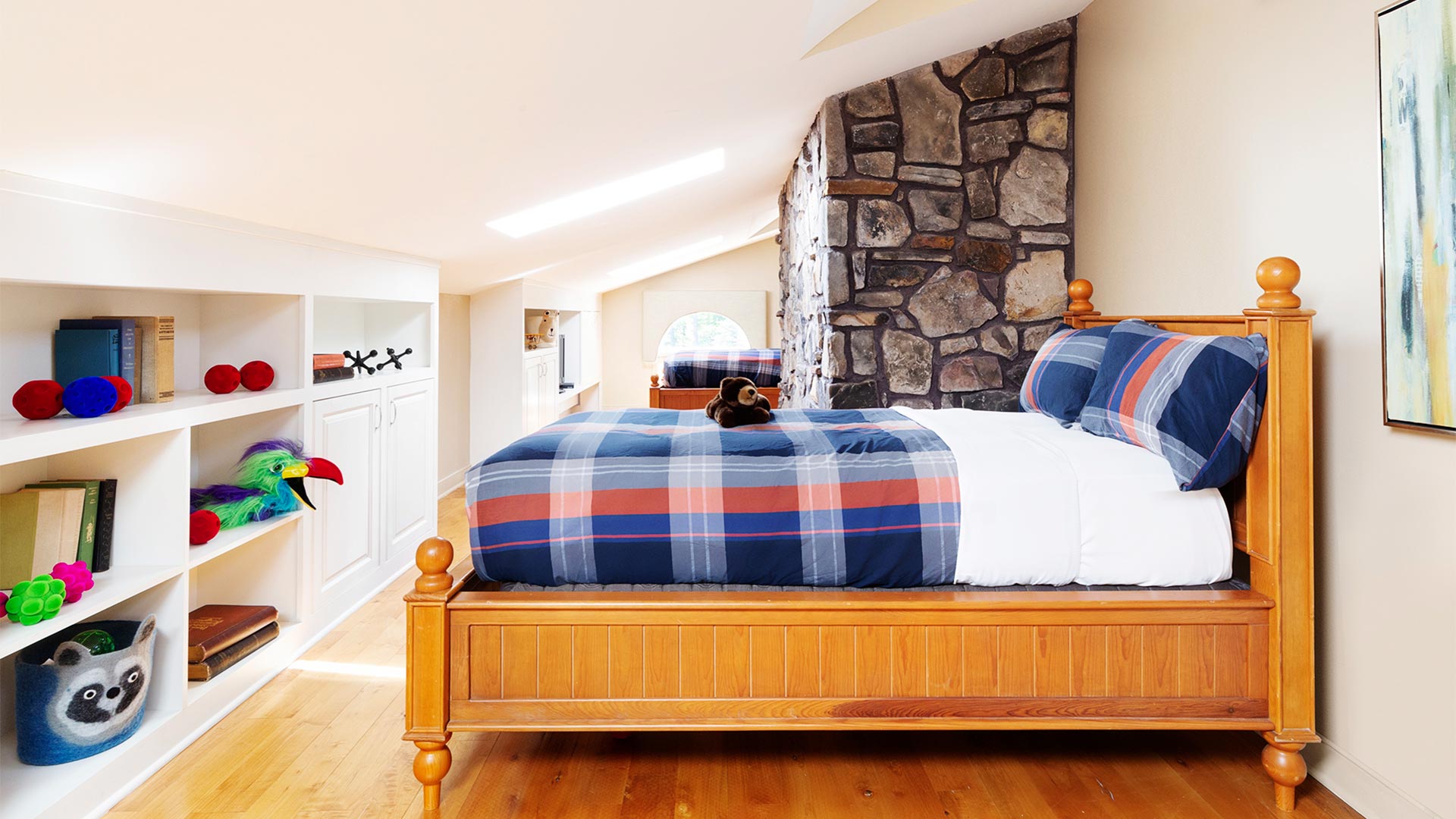 interior shot of a children's bedroom. There is a bed with plaid bedding and a shelving unit across from the bed with toys lining it.