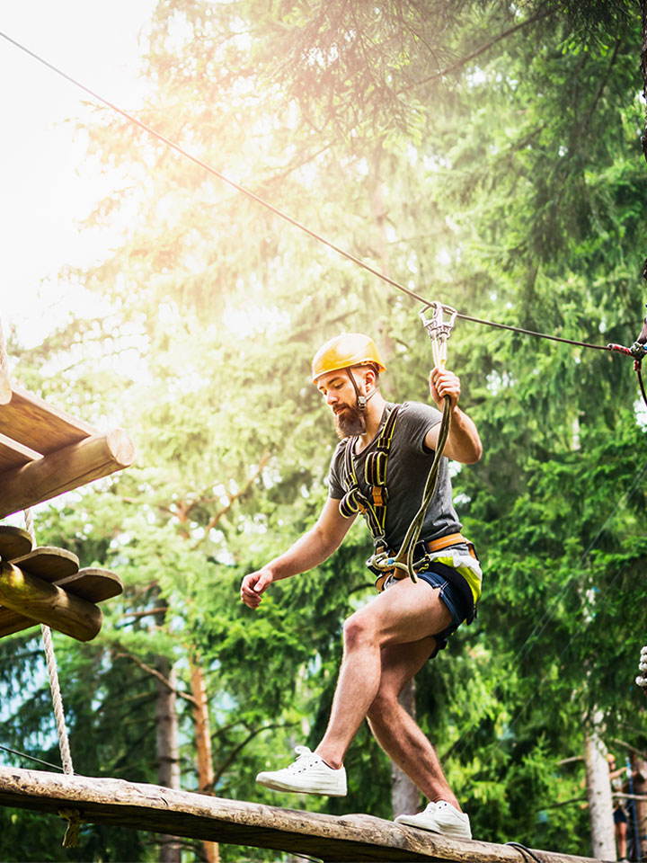 Man moving through a ropes course between trees