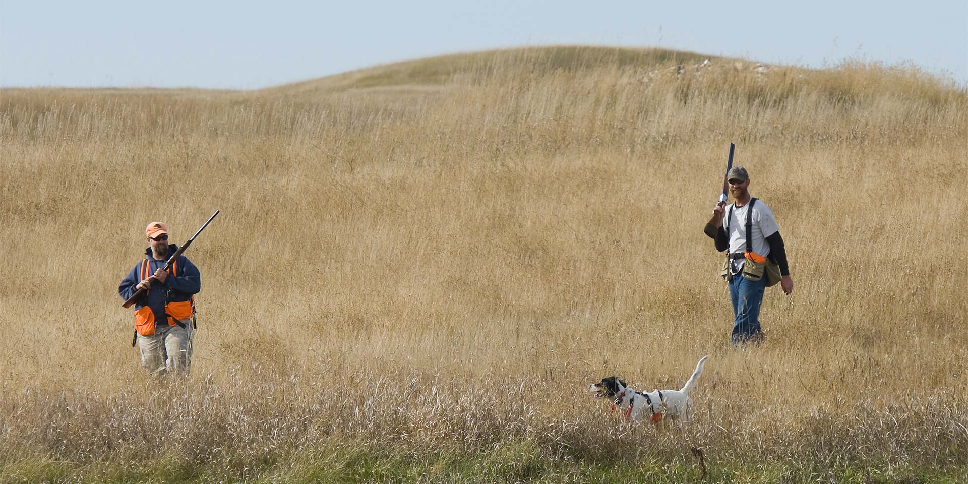 Two men hunting with a dog.