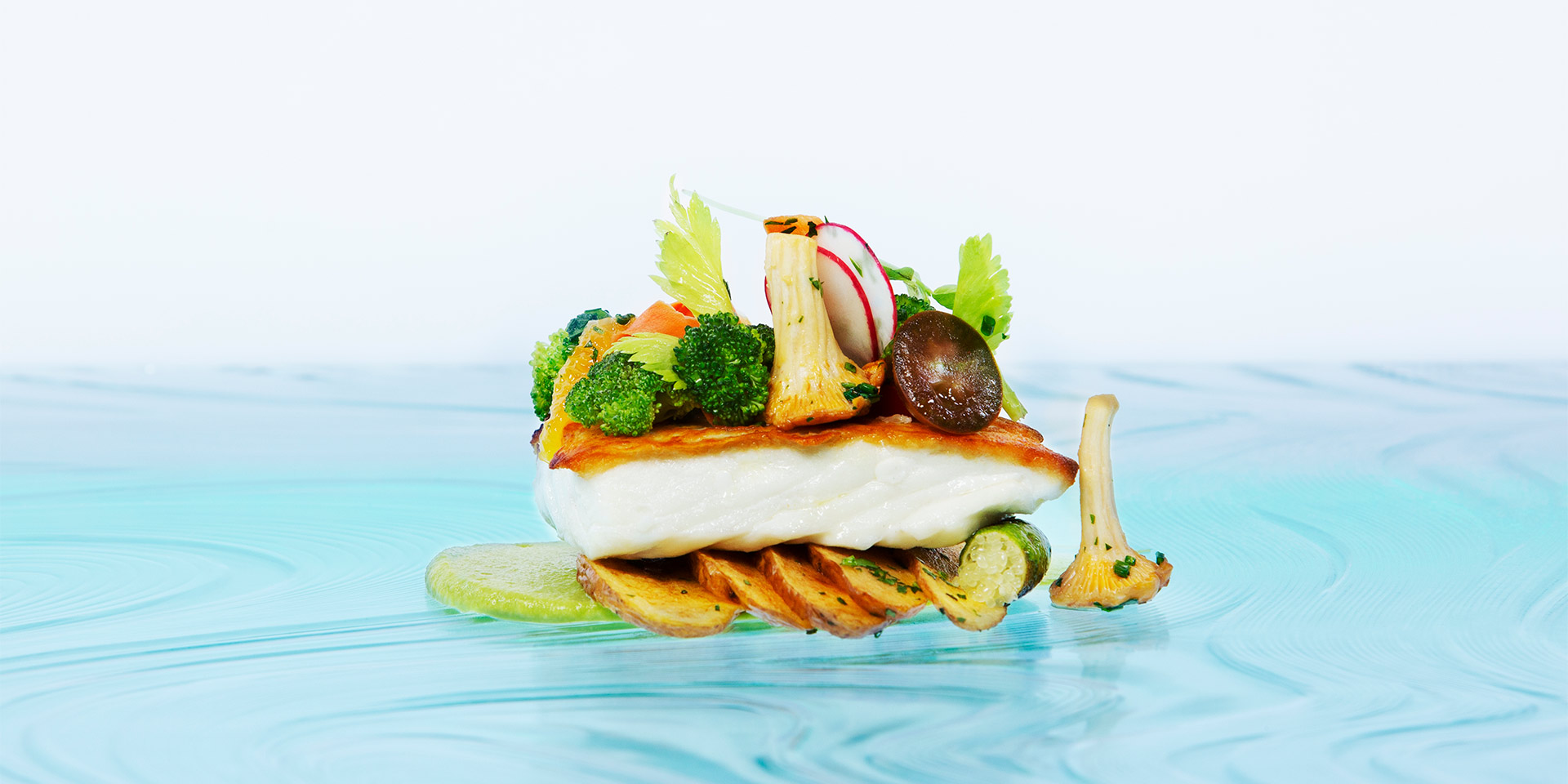 a detail shot of a piece of fish with seared vegetables topping it