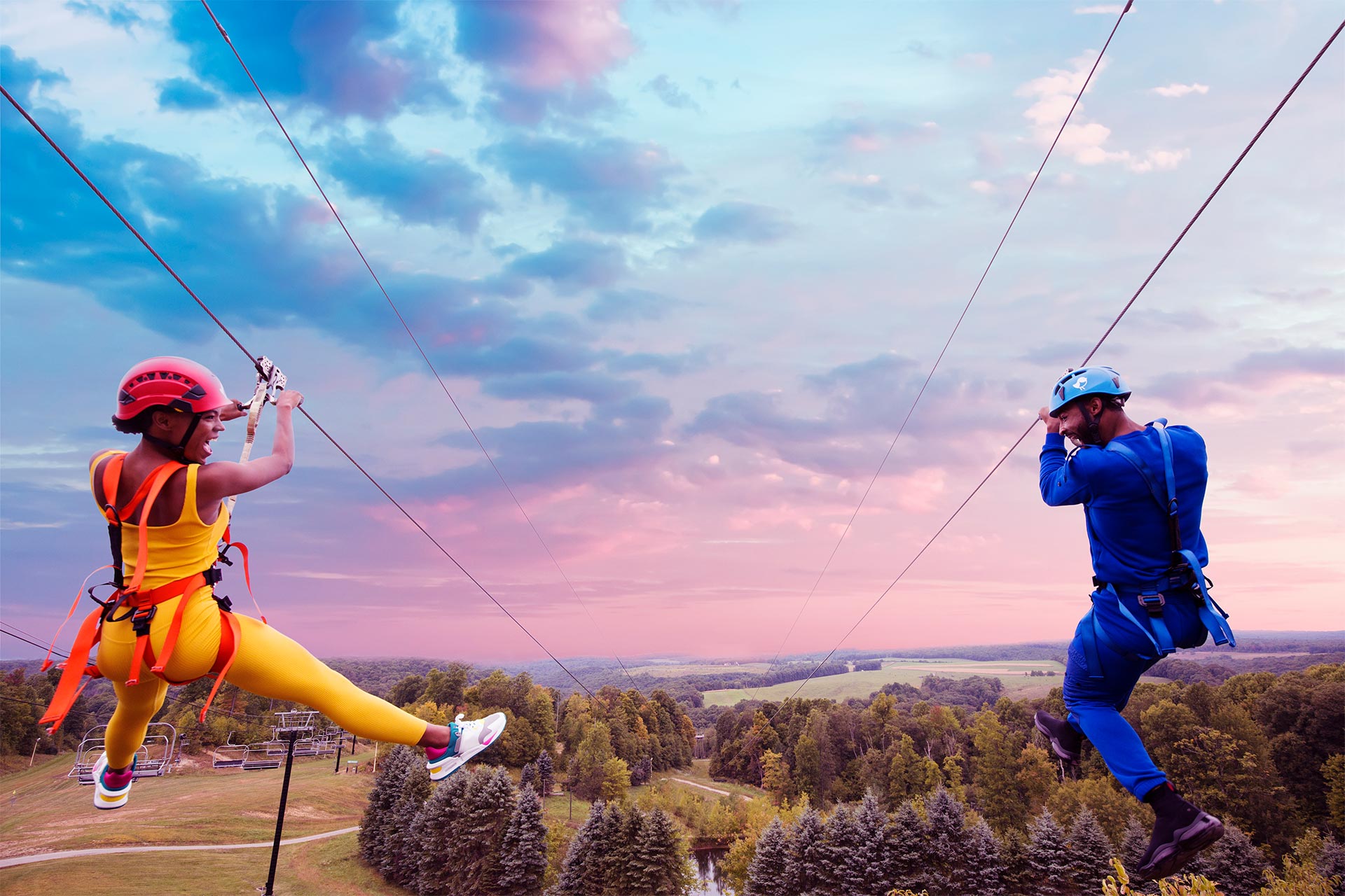 A man and a woman ziplining parallel to one another
