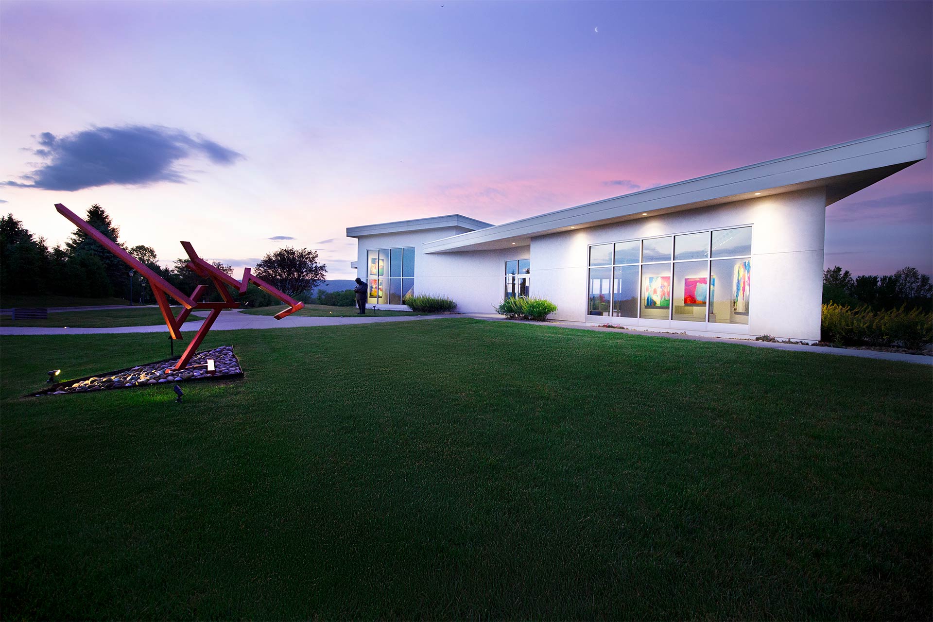 A sculpture in front of a white museum at dusk