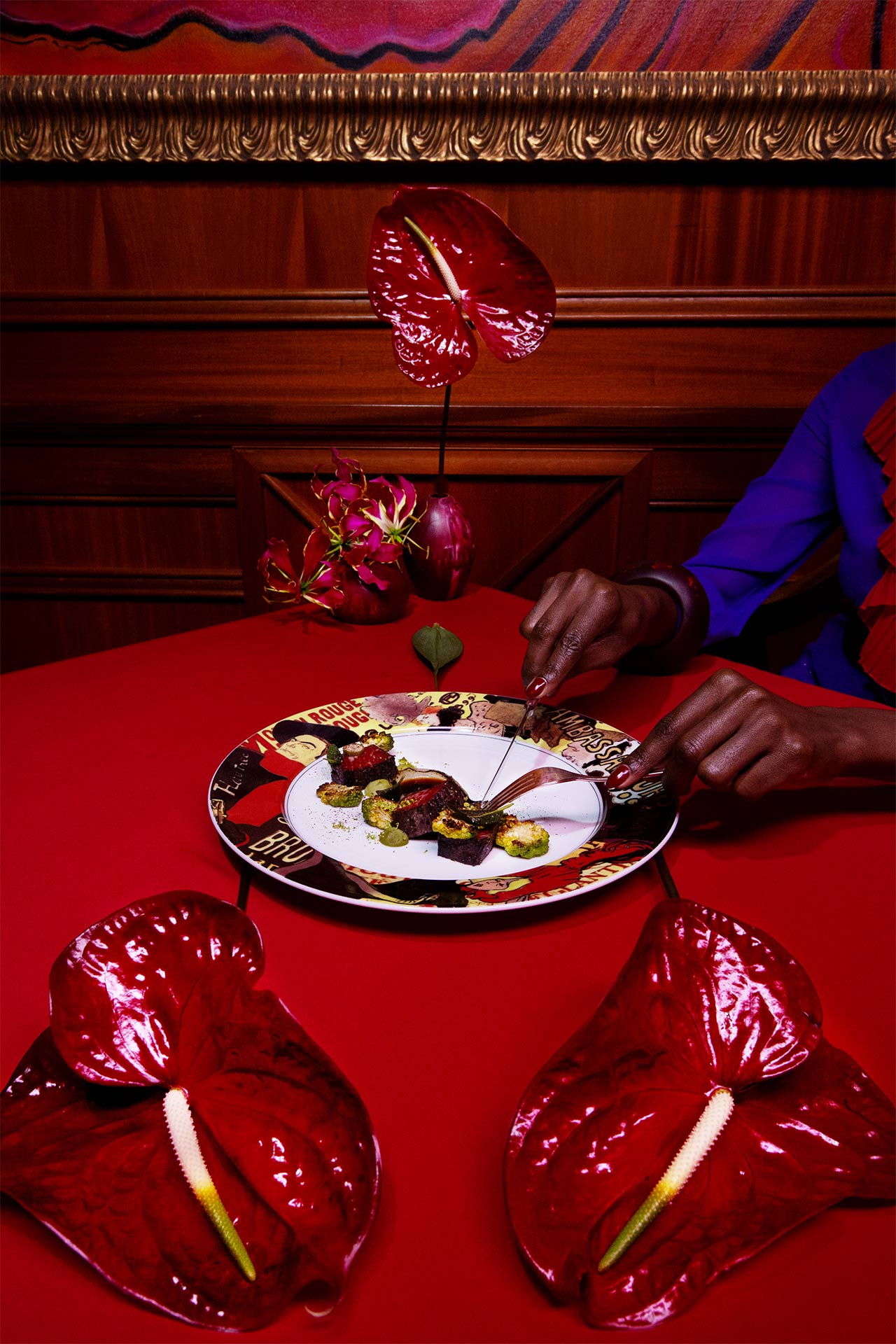 A woman cutting food on a red table in a red room with red flowers