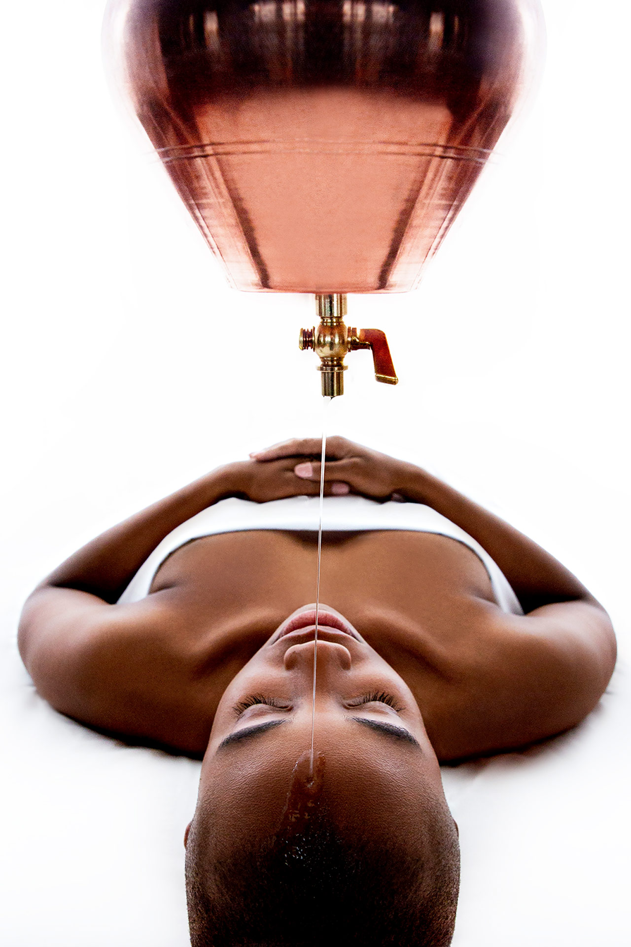 a woman getting a spa treatment where a liquid is dripped onto her head