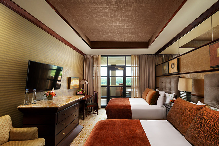a room with two large beds that has a glass door to a balcony