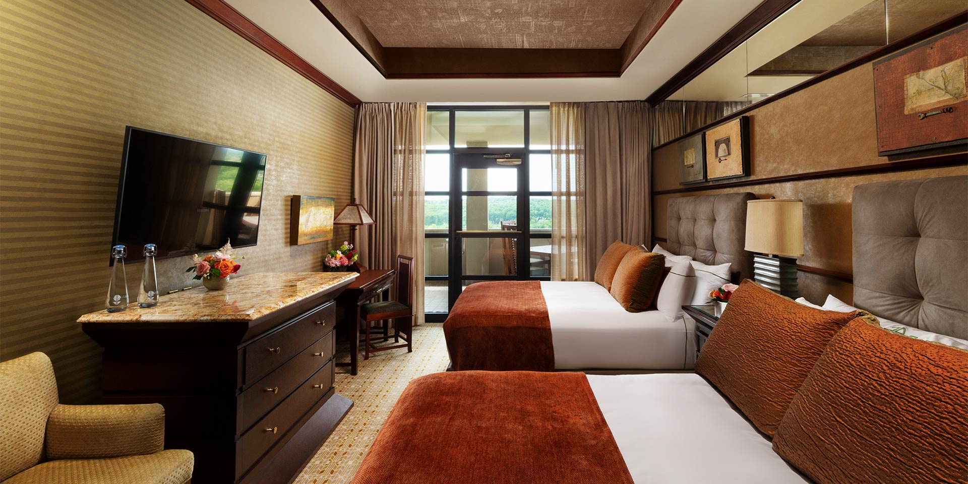 a room with two large beds that has a glass door to a balcony