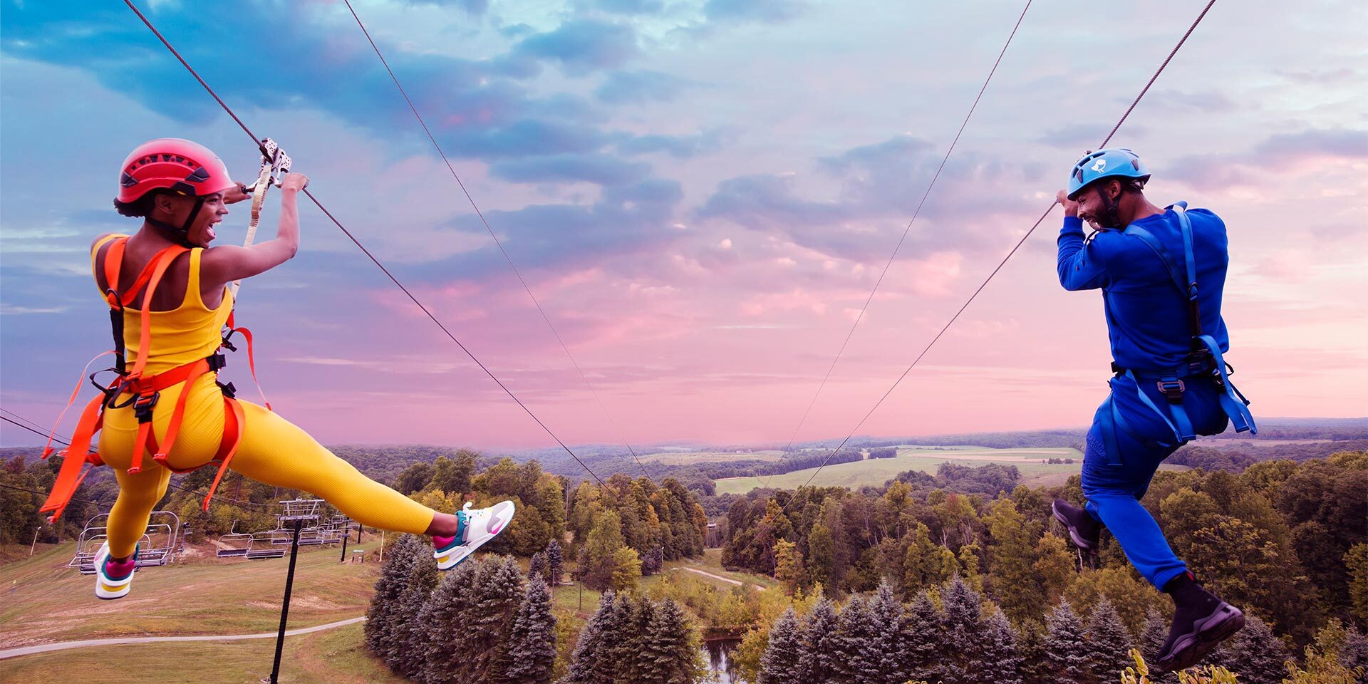 man and woman ziplining parallel to each other