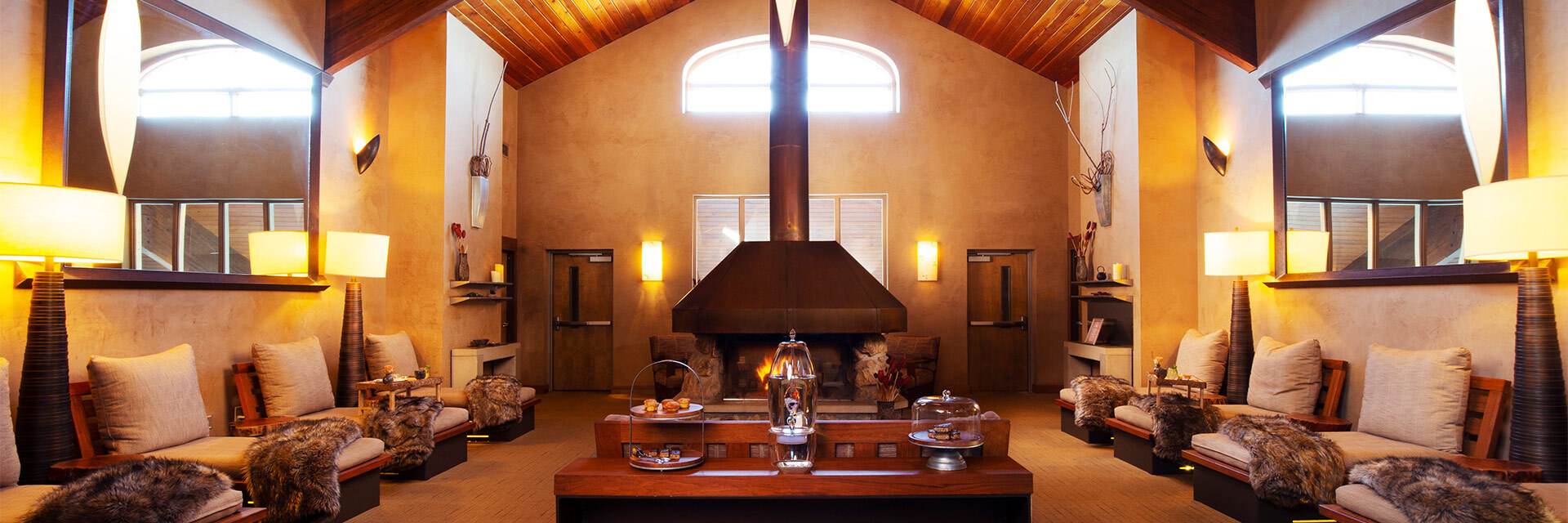large room with seating on either side and a table in the middle and fireplace in the back, dimly lit