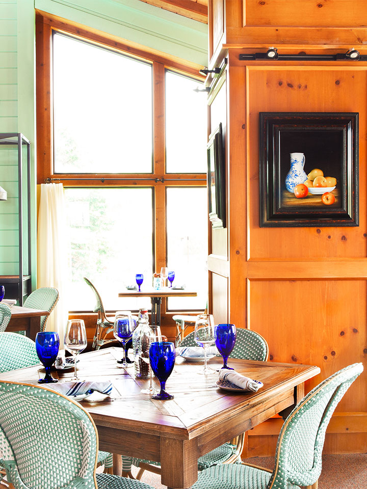 A dining table with blue glasses surrounded by teal chairs in a kitchen.