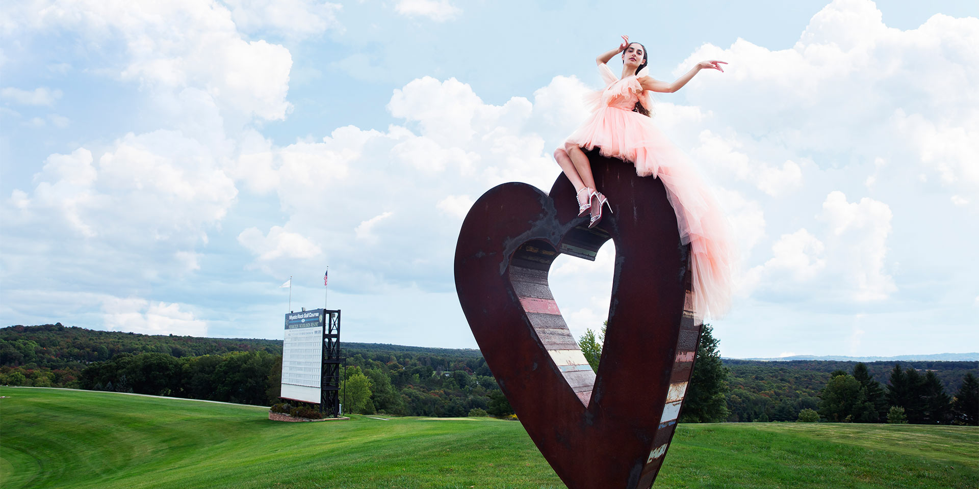 Woman on a heart statue in a a field