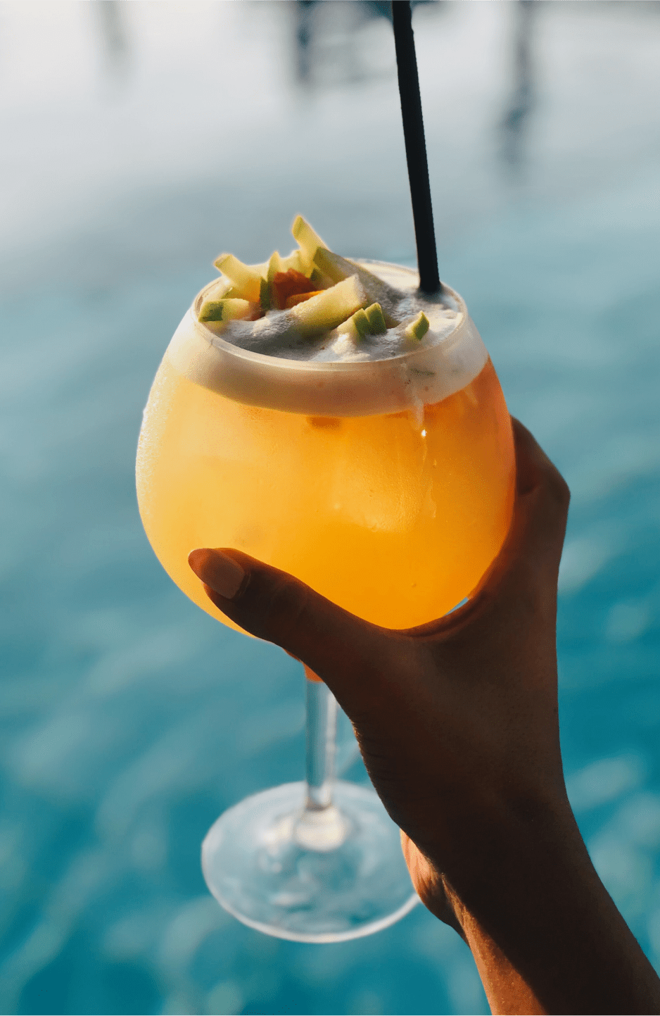 Hand holding a drink with water in the background