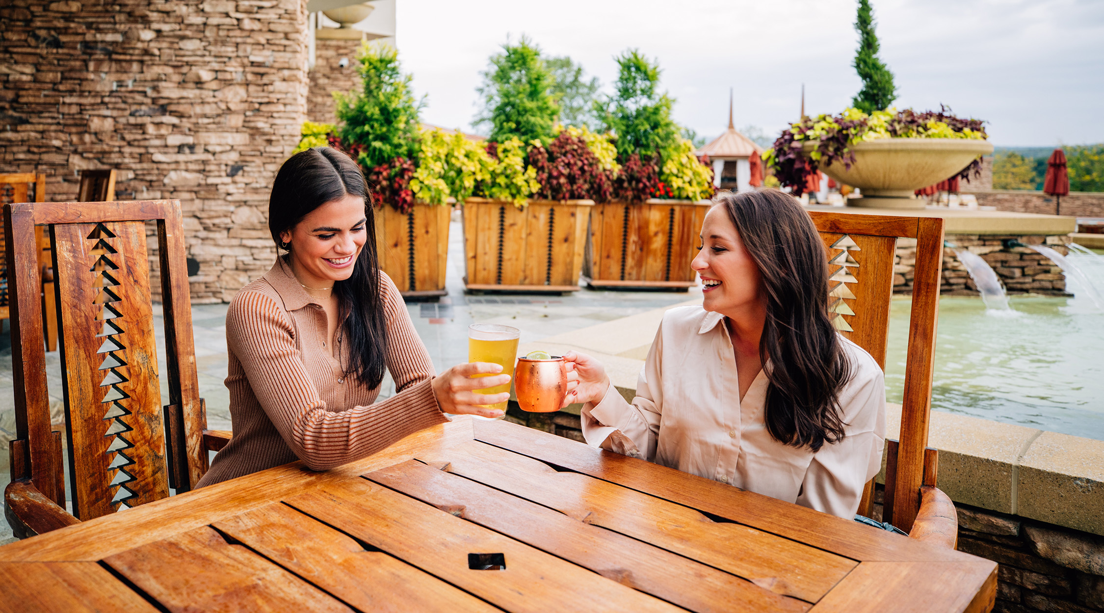 Two women toasting with drinks on a patio
