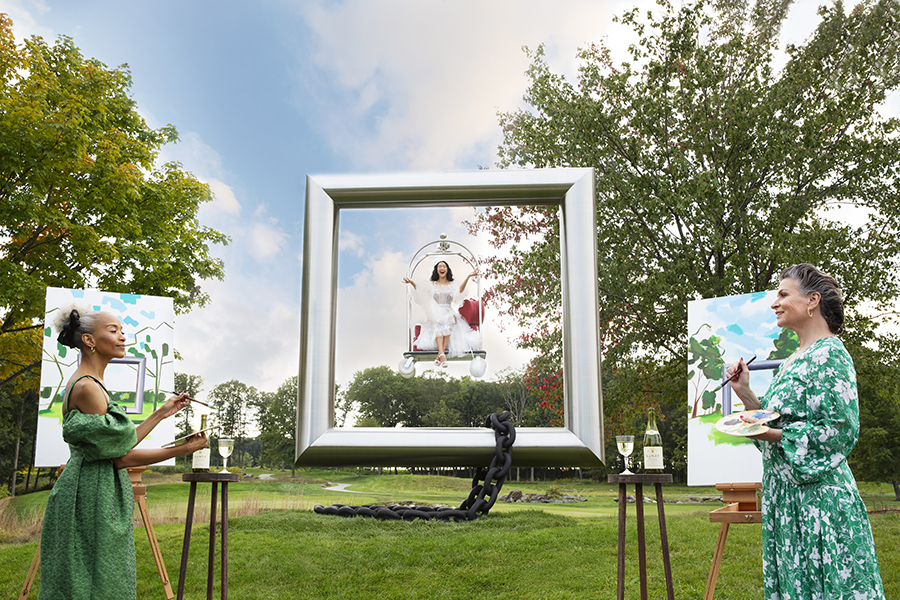 two women painting while a woman swings in the background