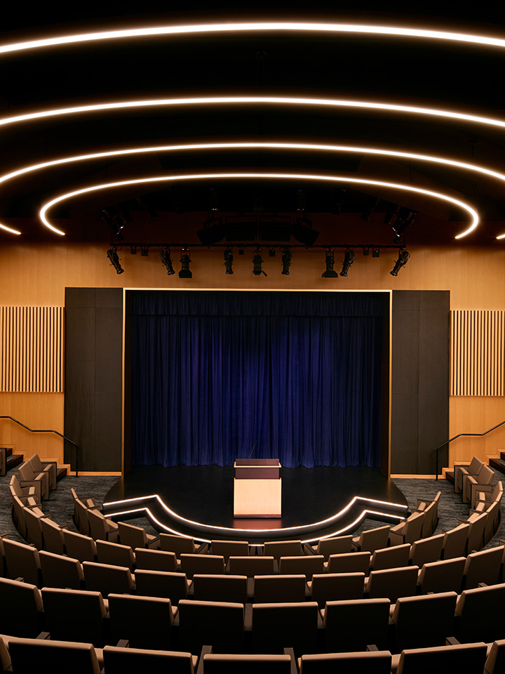 Large lecture hall boardroom with a bronze colored wall and dark blue curtain