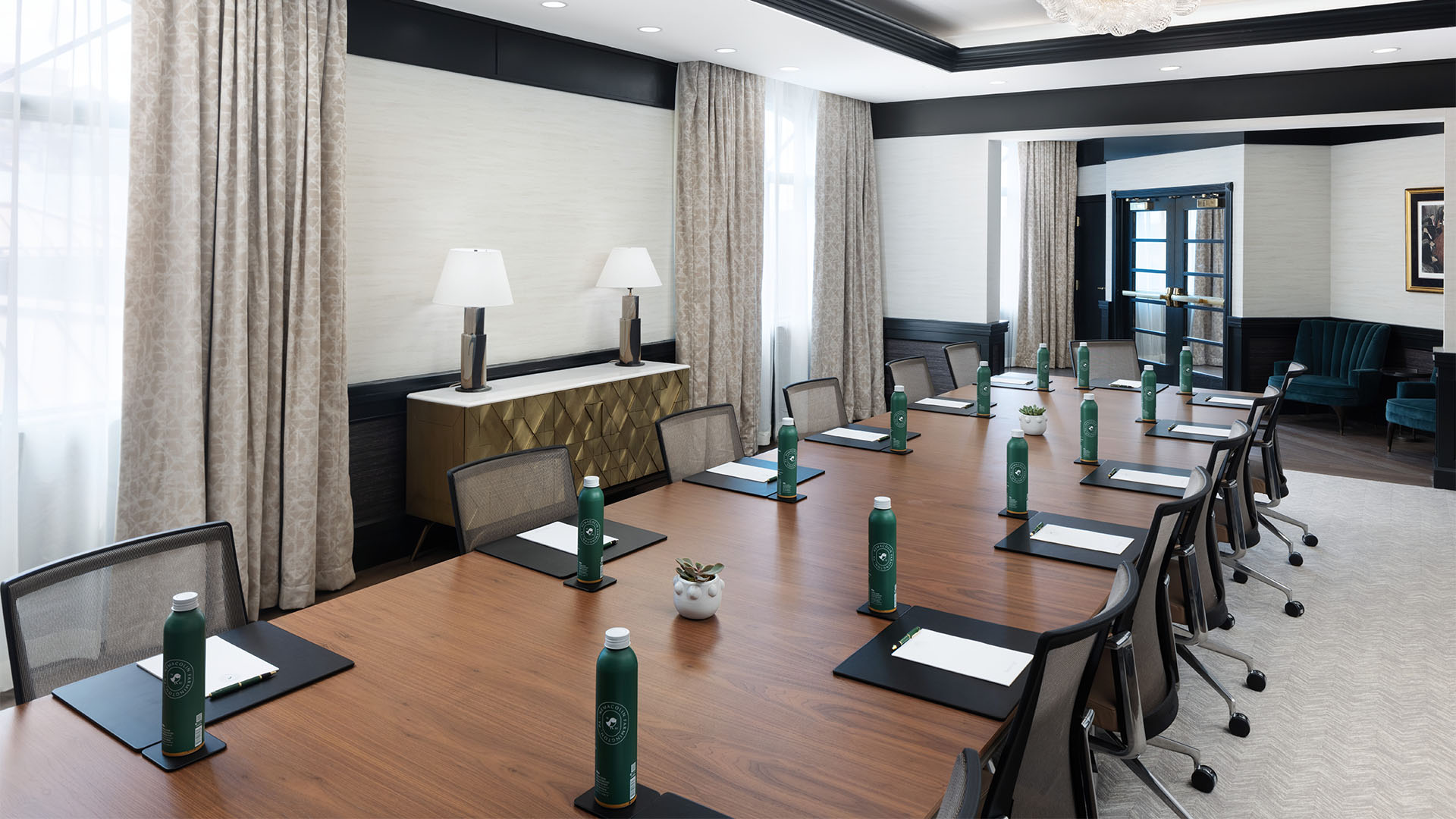 Large rectangle wooden table setup for meeting with water bottles and folders.