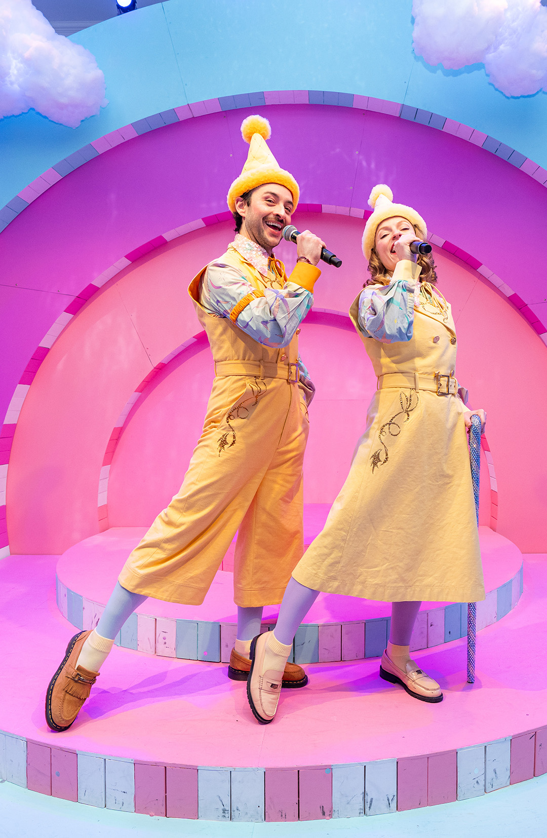 People singing on a bright colored stage wearing elf hats