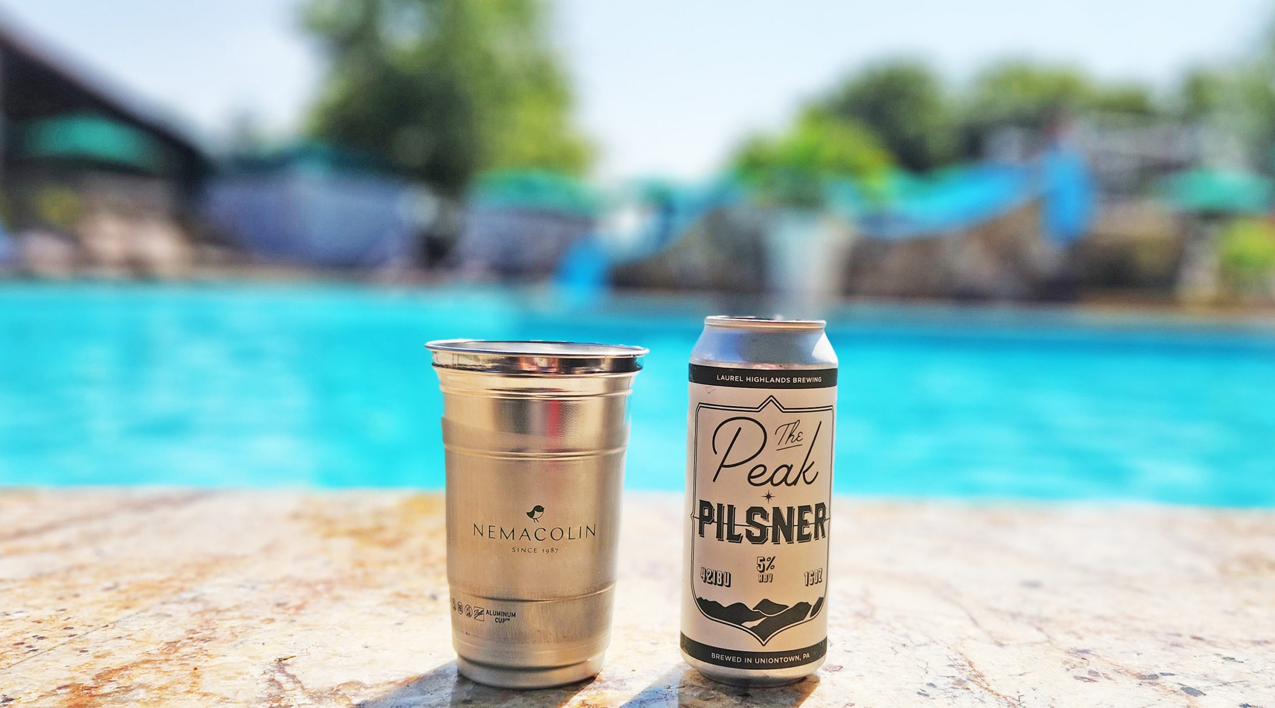 A beer cup and beer can on a pool deck