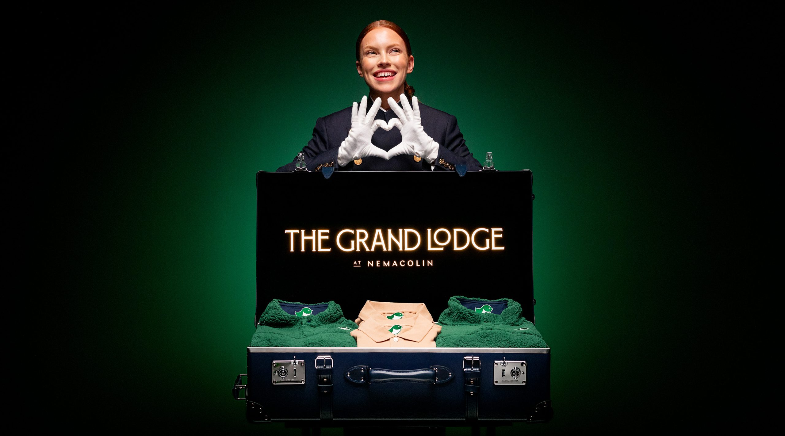 open suitcase for The Grand Lodge at Nemacolin with a smiling woman making a heart with white-gloved hands