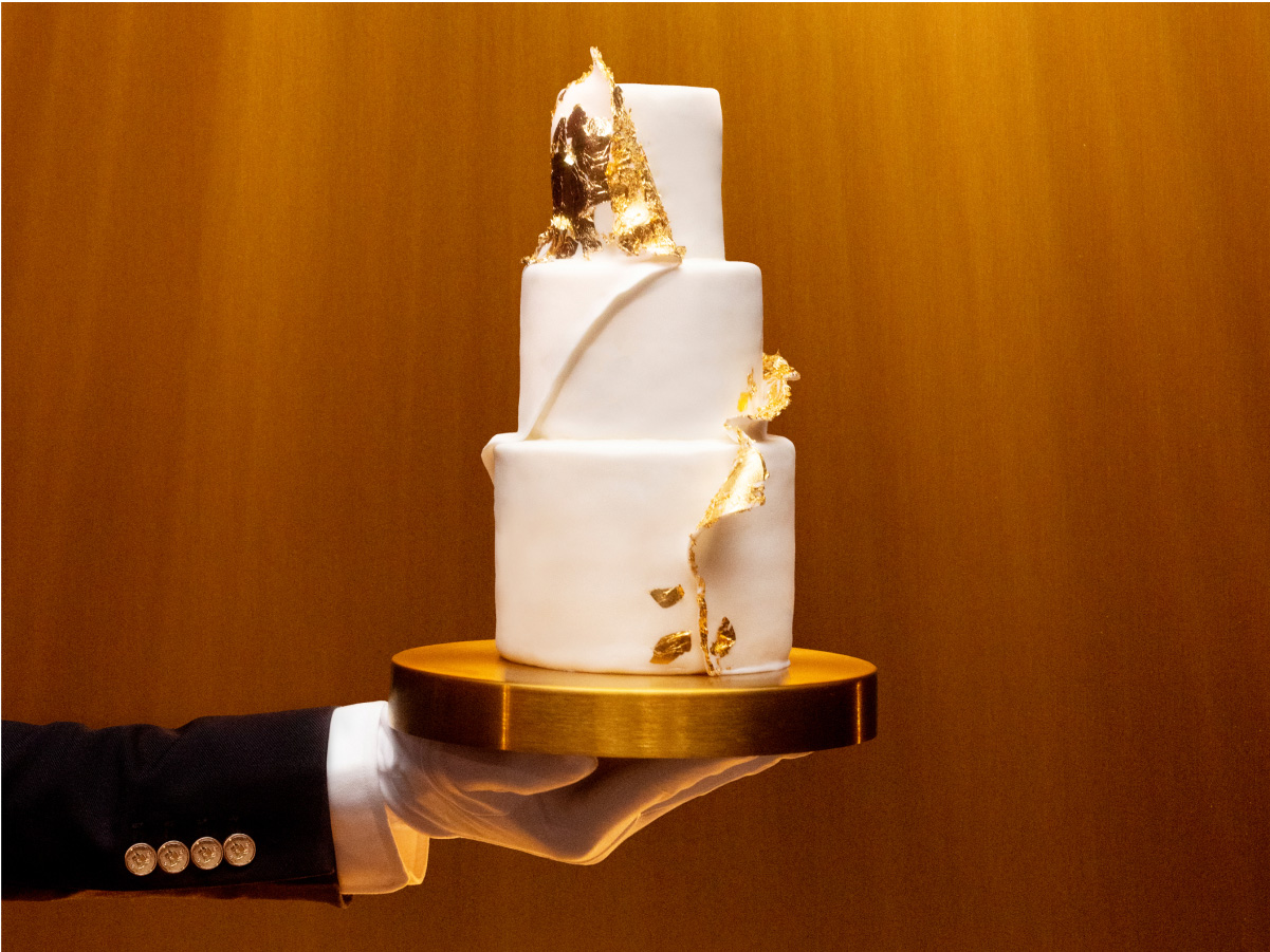 White cake being held on a gold tray with gold background