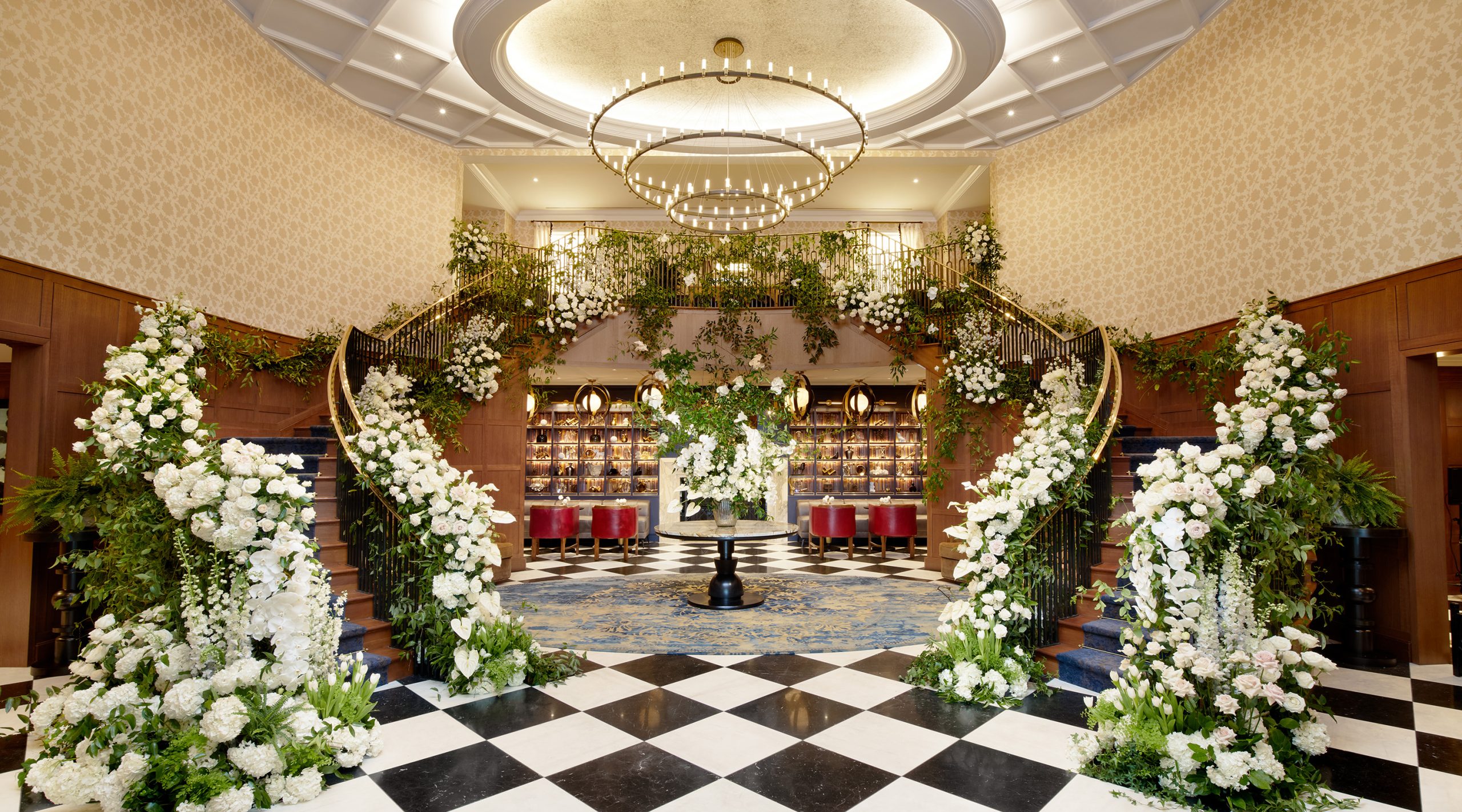 Lobby of The Grand Lodge at Nemacolin with white flowers decorating the lobby, including both sides of the rails on the split staircase