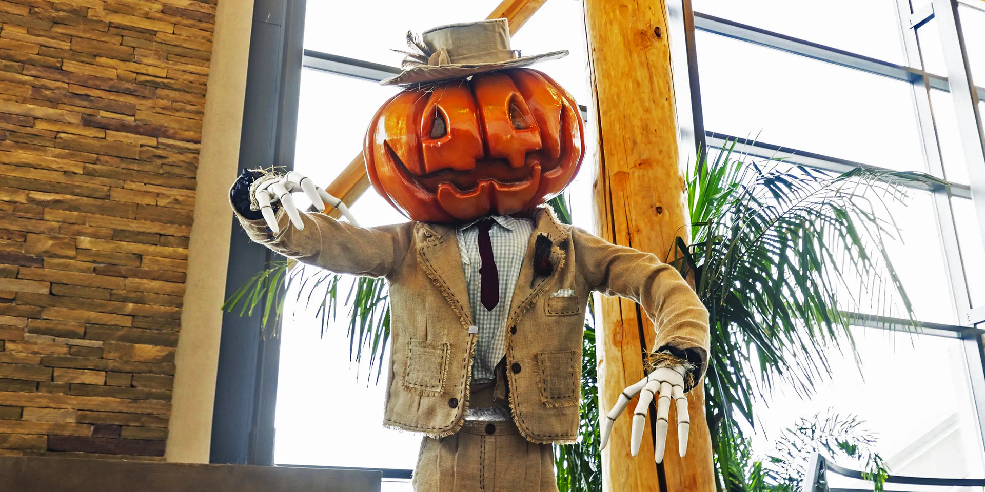 Pumpkin head man with skeleton hands dressed in a burlap suit