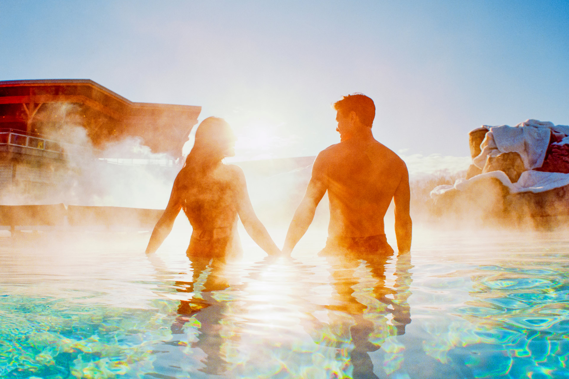 a man and woman holding hands in a steaming pool