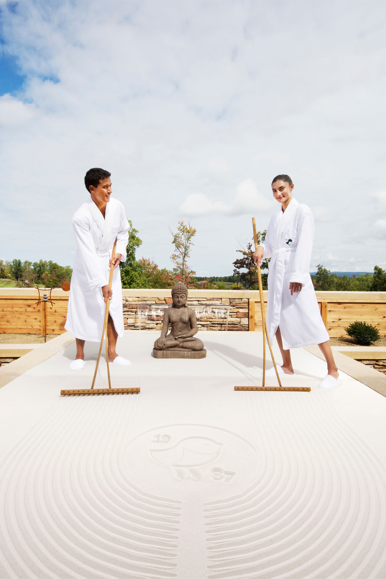 two people in bathrobes with a Buddha engaging in life size sand tray therapy