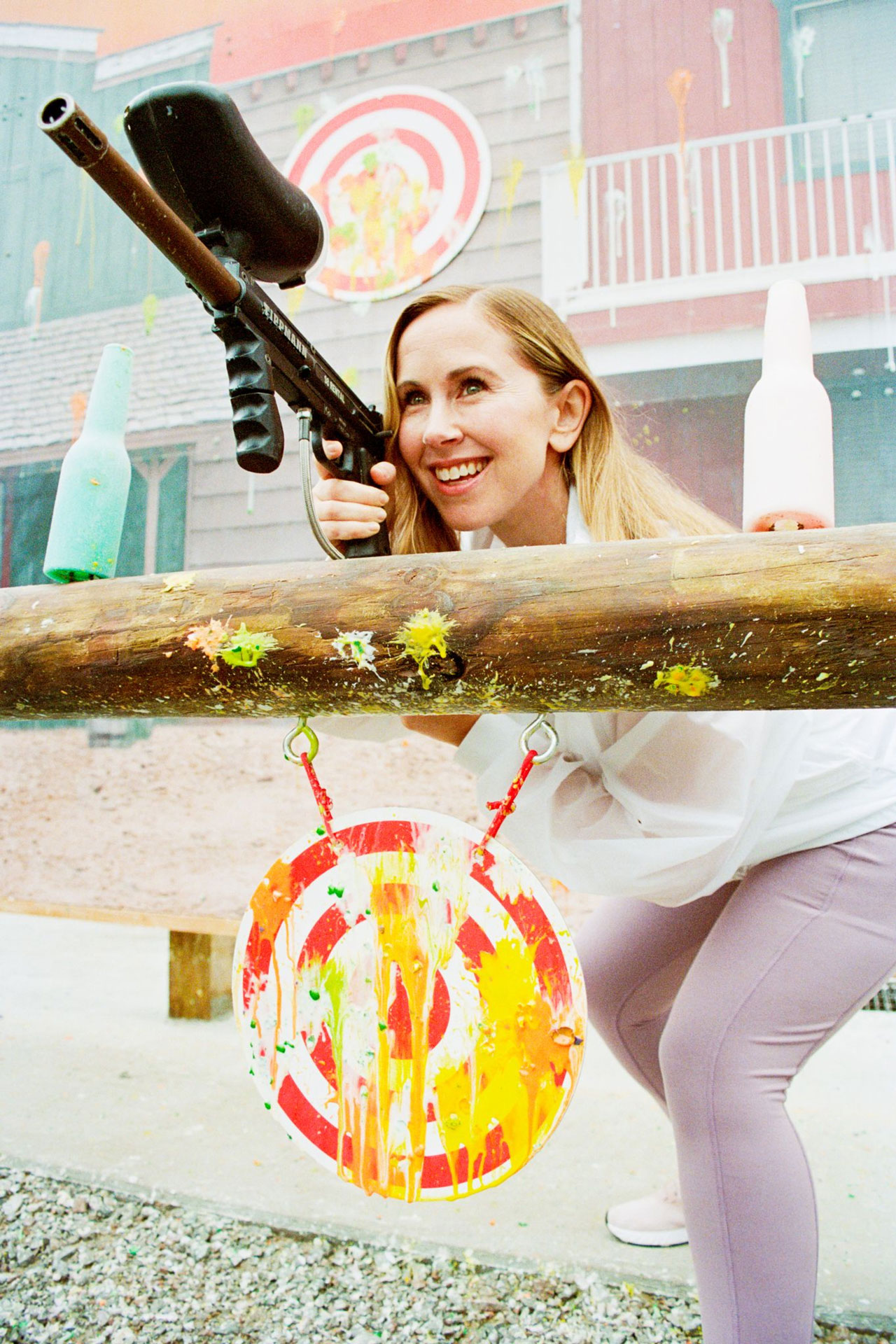 a woman smiling while playing paintball