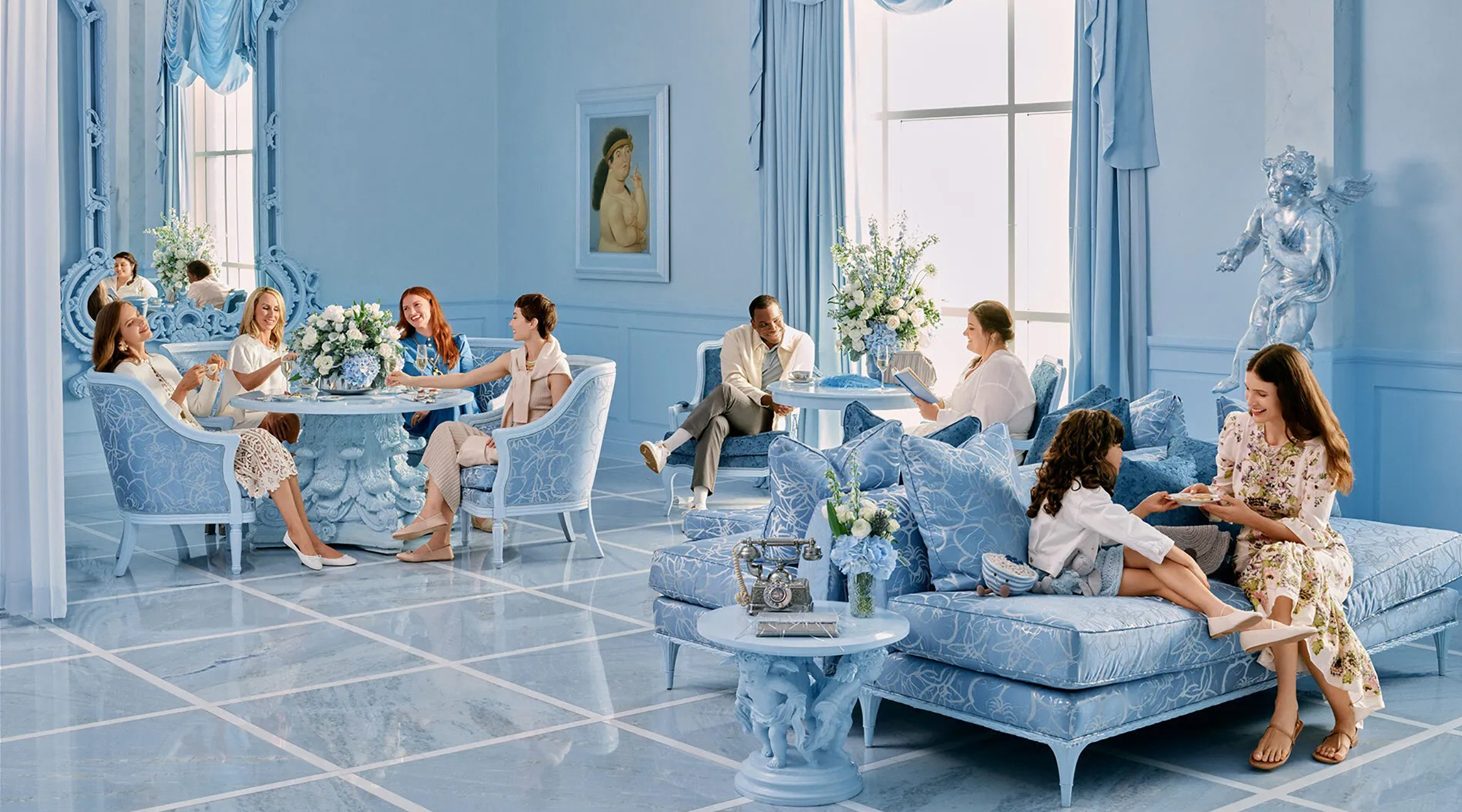 Eight people seated and dining in a blue room with blue walls, flooring, florals, and furniture at The Blue Room at Nemacolin