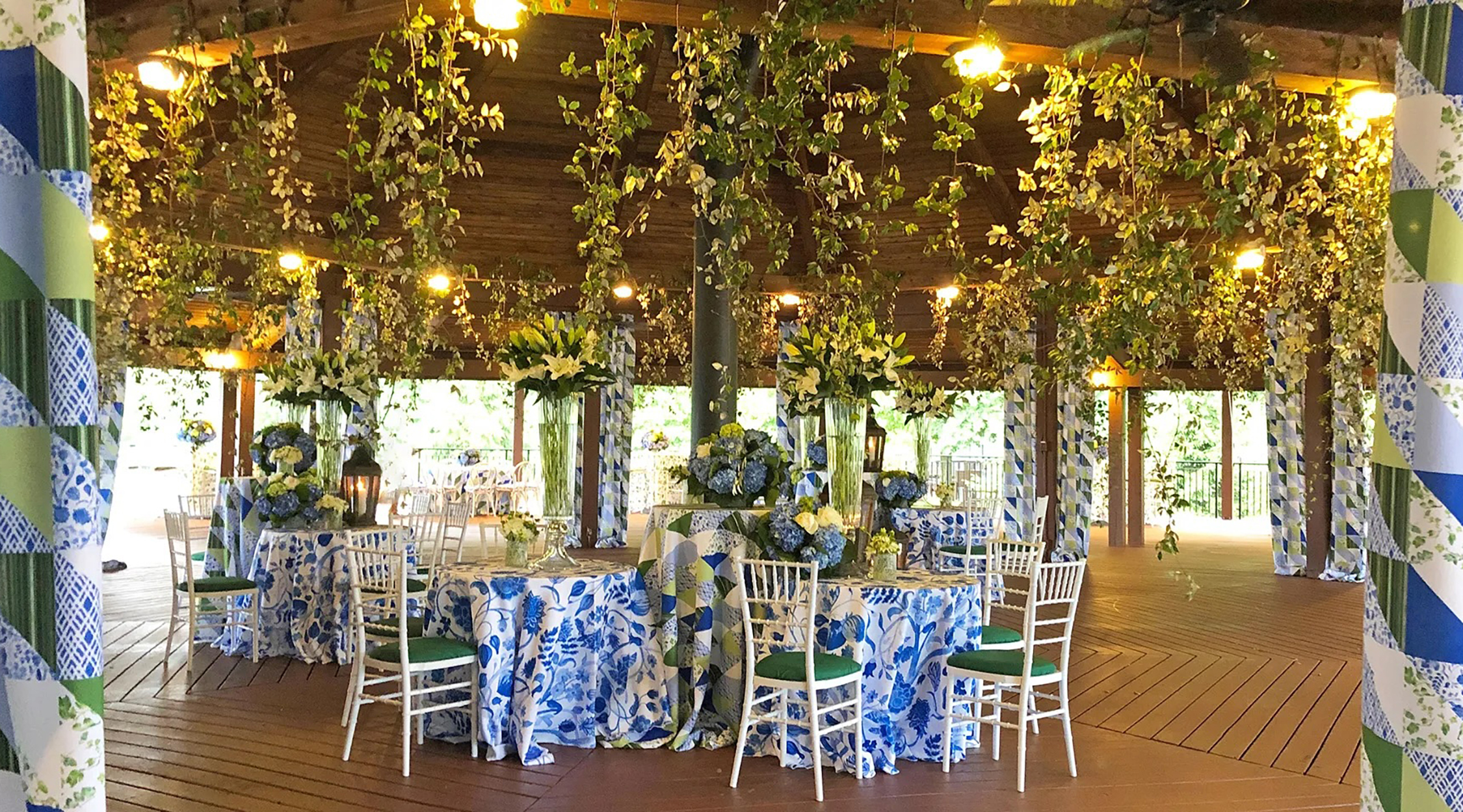 An outdoor pavilion decorated for a wedding with accents of green vines and blue florals, located at the Panorama Pavilion at Nemacolin