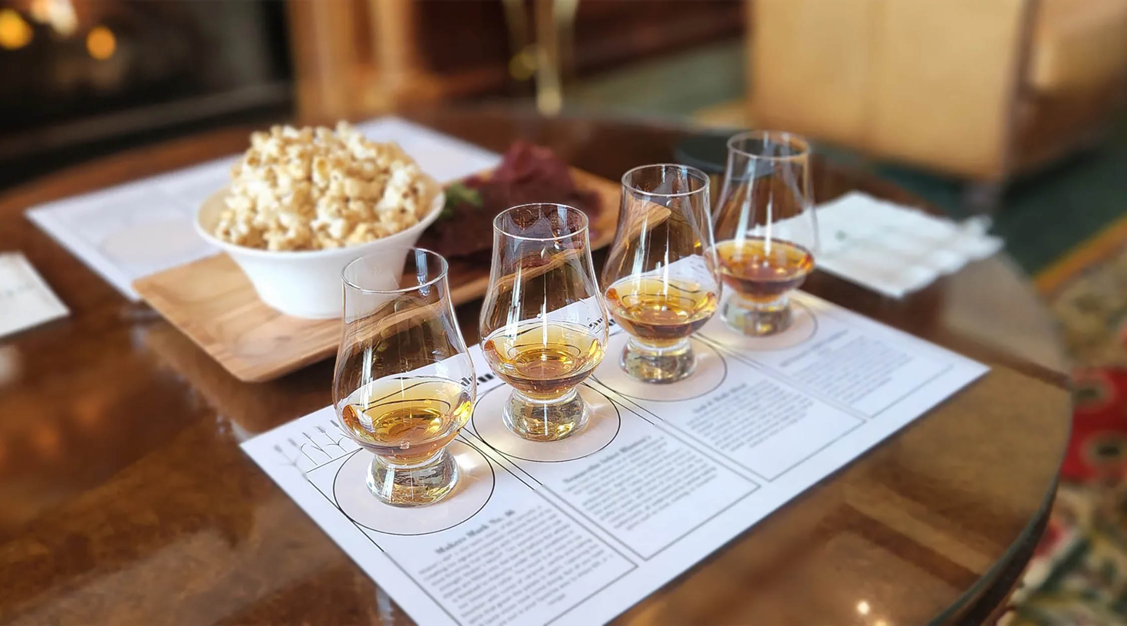 Four whiskey glasses arranged on a tasting mat, ready for a guided whiskey tasting experience at Nemacolin's Hardy Room.