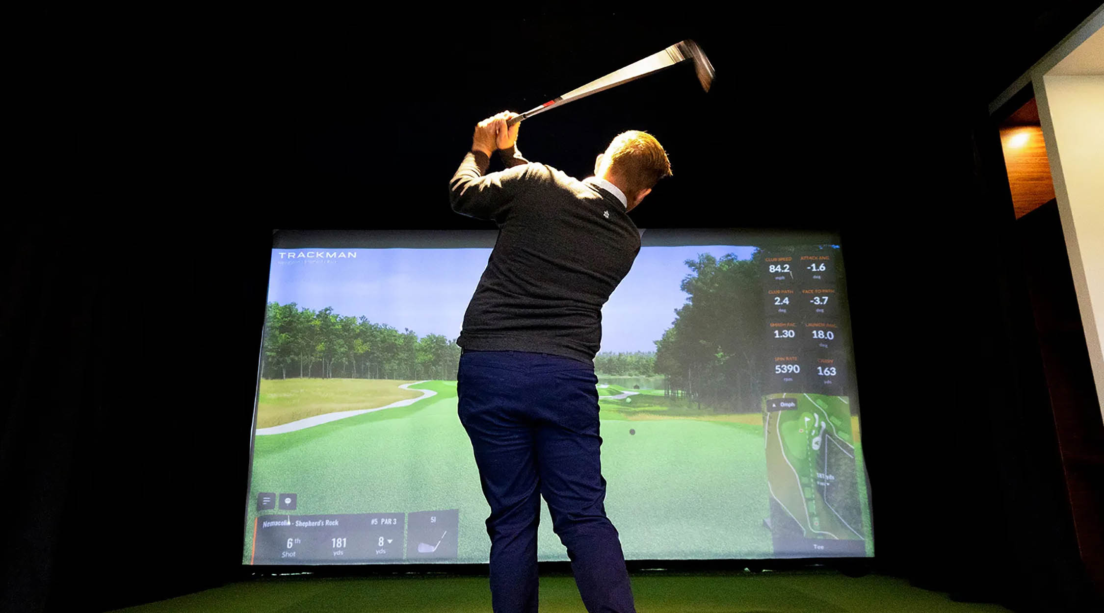 A man perfecting his golf swing using the Trackman Simulator at Nemacolin's Golf Academy during the winter season.