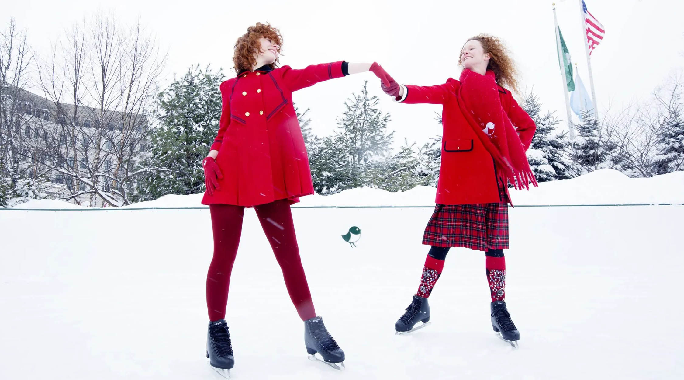 Two women in red coats ice skating on Nemacolin's outdoor ice rink, creating a magical winter wonderland moment.