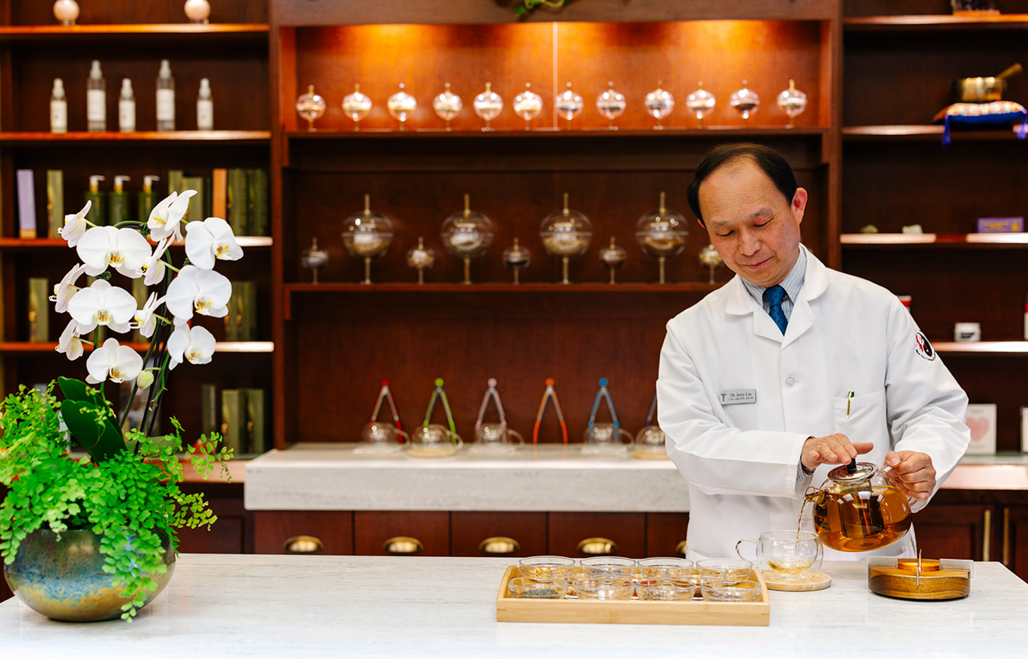 man behind a counter pouring herbal tea