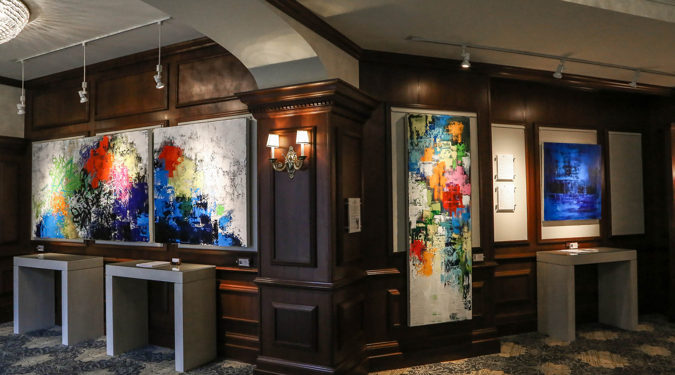 Corner of Nemacolin art collection gallery with paintings displayed on dark wood wall