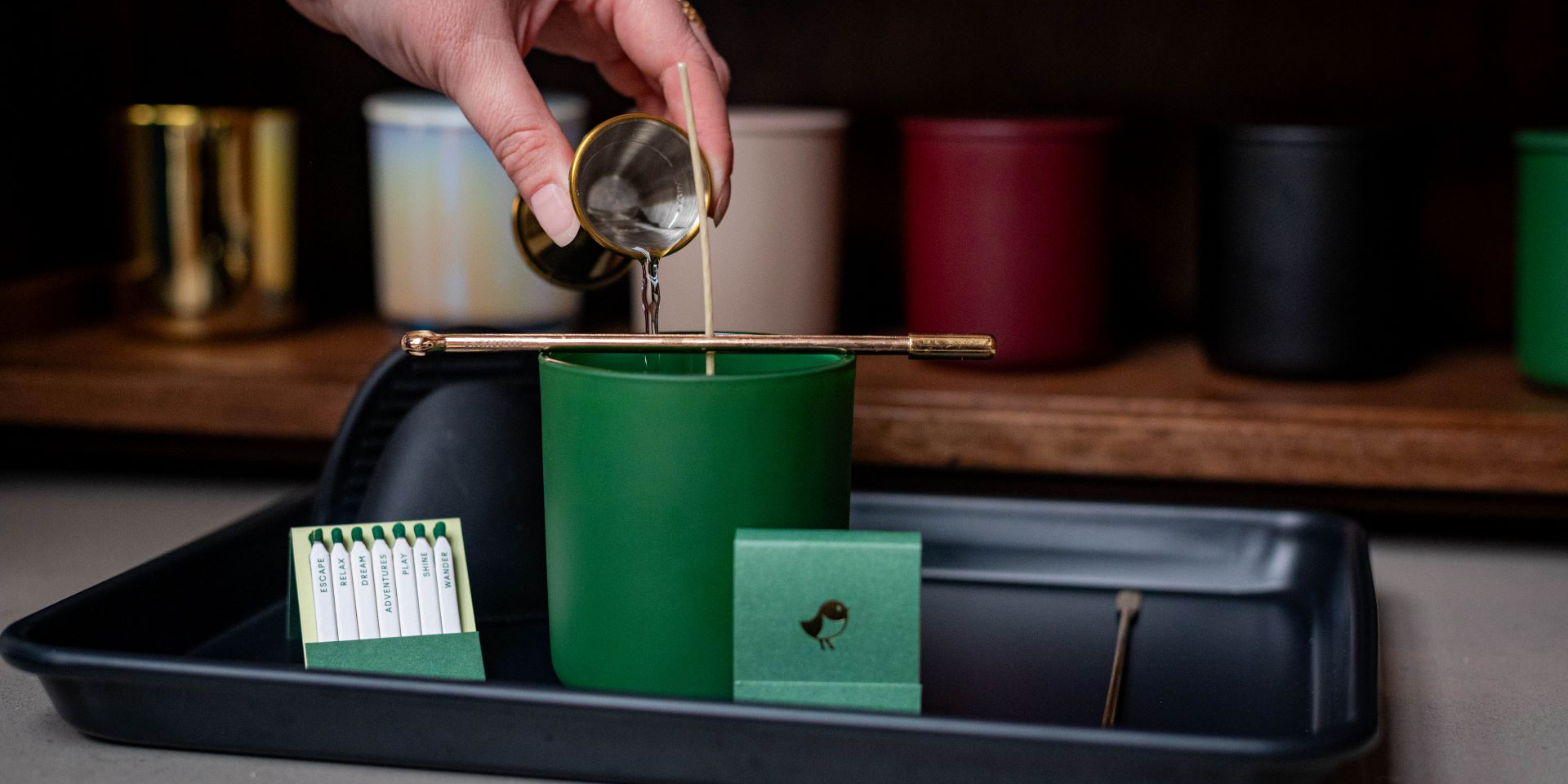 hand pouring wax into candle vessel