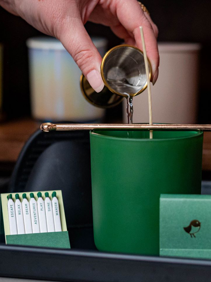 hand pouring wax into candle vessel