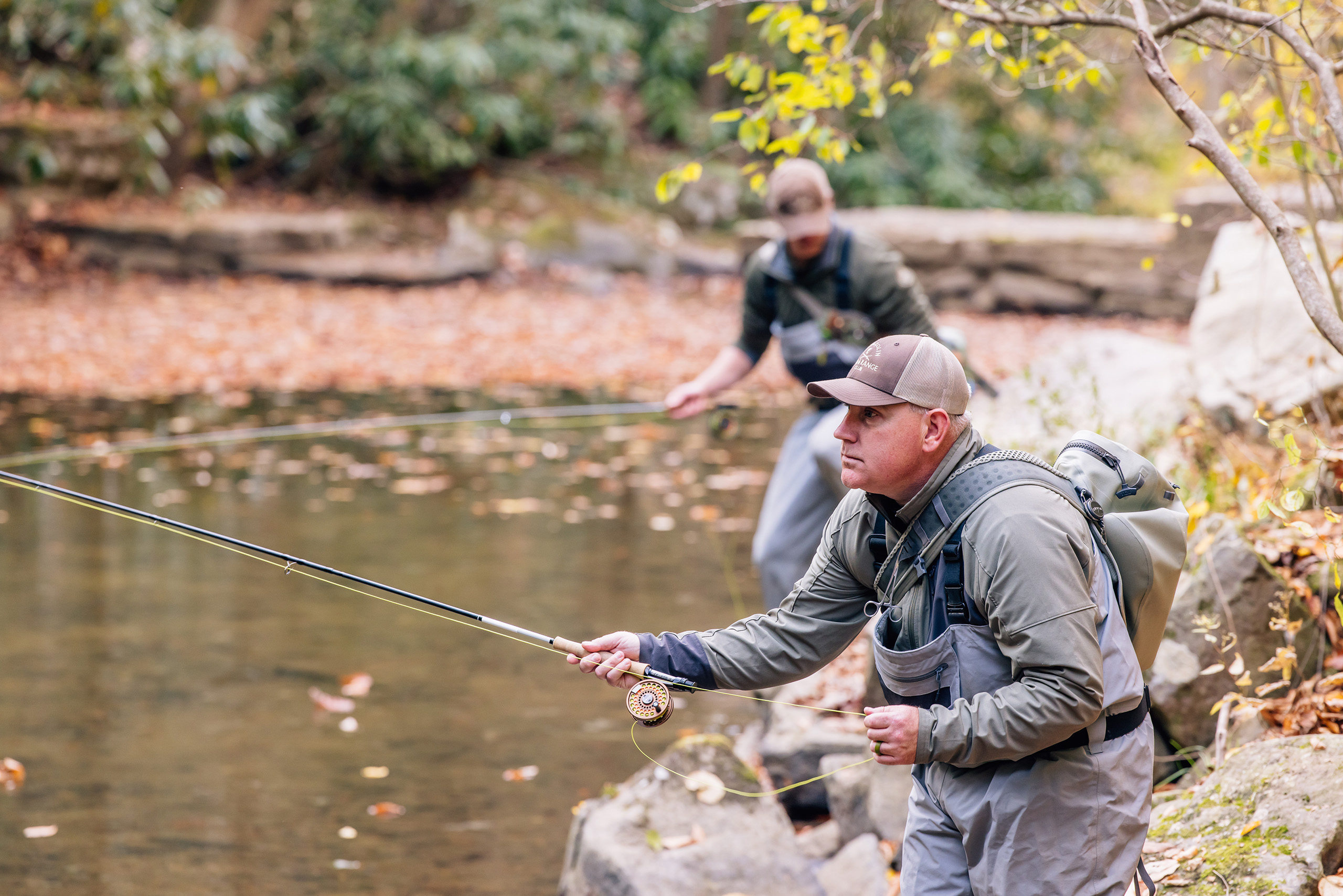 man standing in a creek with a fly fishing rod