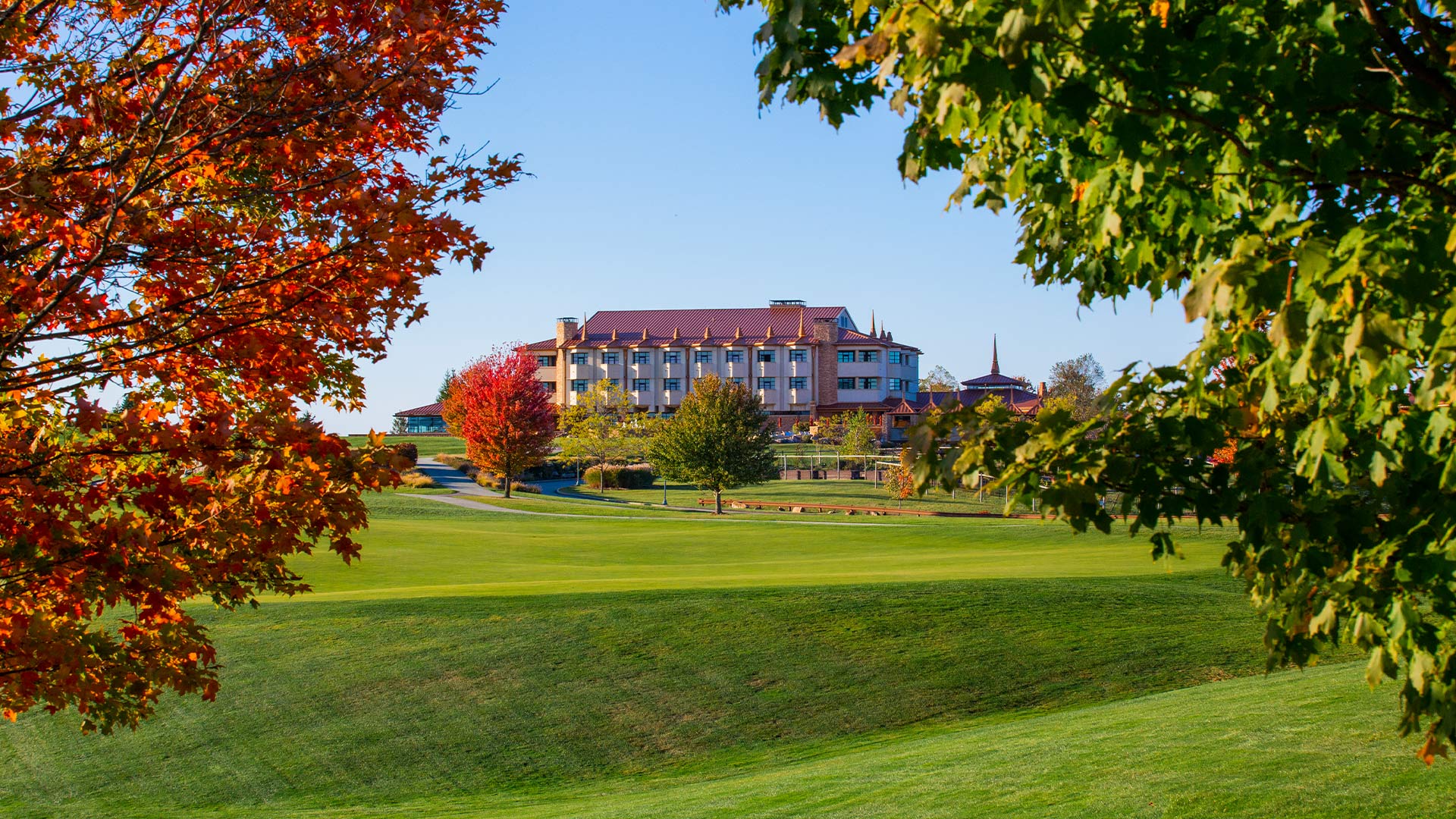 The Falling Rock hotel at Nemacolin framed by fall leaves and the green of the Mystic Rock Golf Course