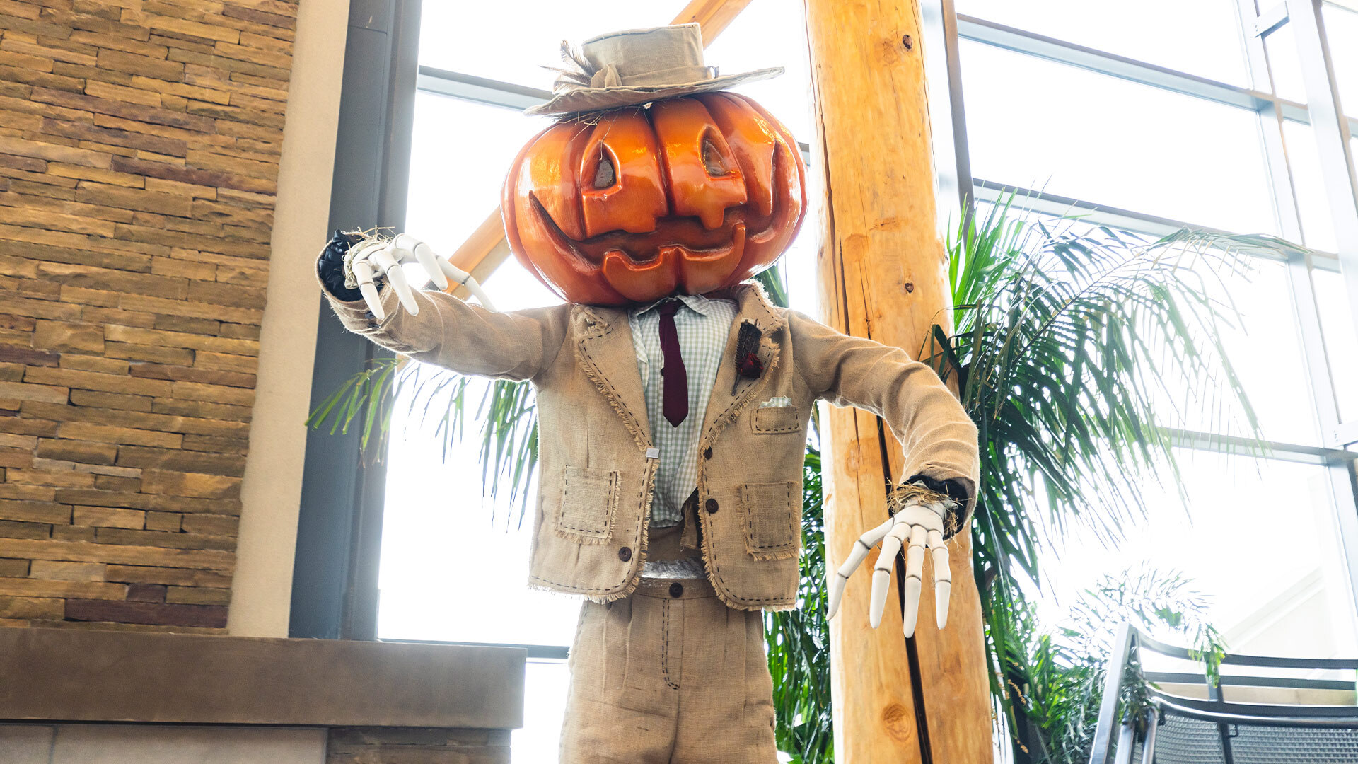 Pumpkin head man with skeleton hands dressed in a burlap suit